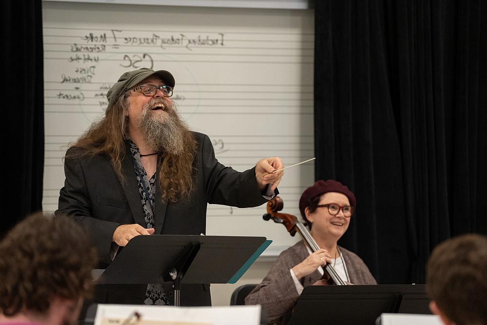 Two instructors smile as they lead an ensemble practice.